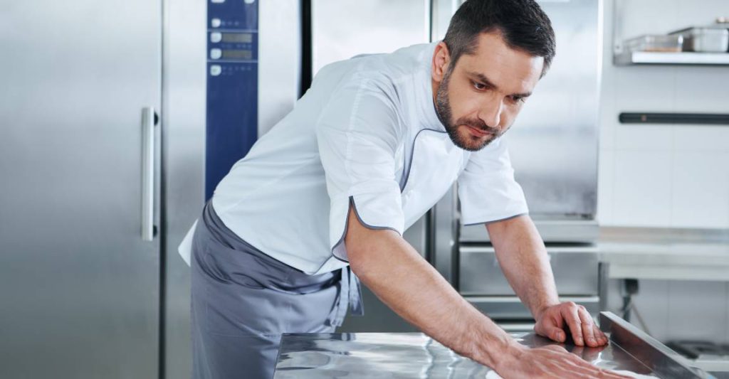 A restaurant manager and owner taking the time to clean his kitchen to adhere to safety protocols.